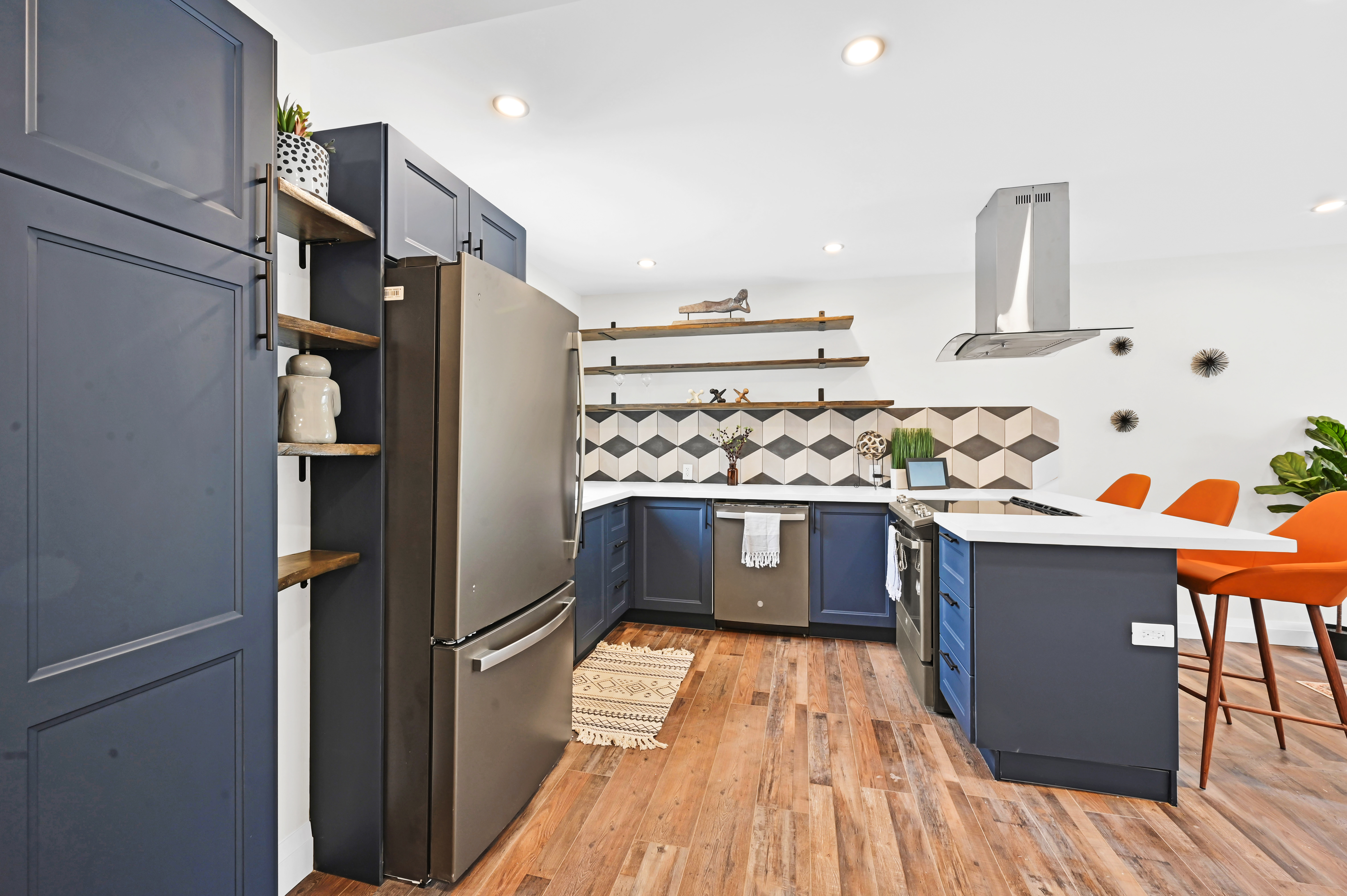 Premium finished kitchen with dramatic navy cabinets, geometric backsplash, and warm wood floors — Kron, Hamilton | MTC Renovations